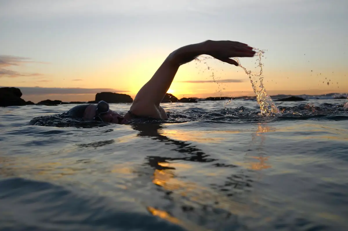 Open water swimmer mid-stroke at sunset